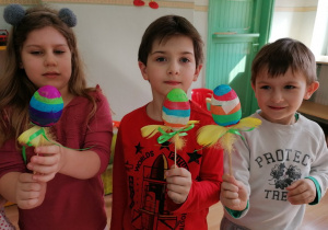 Dzieci pokazują wykonane pisanki - jajka akrylowe oklejane kolorowymi paskami bibuły.